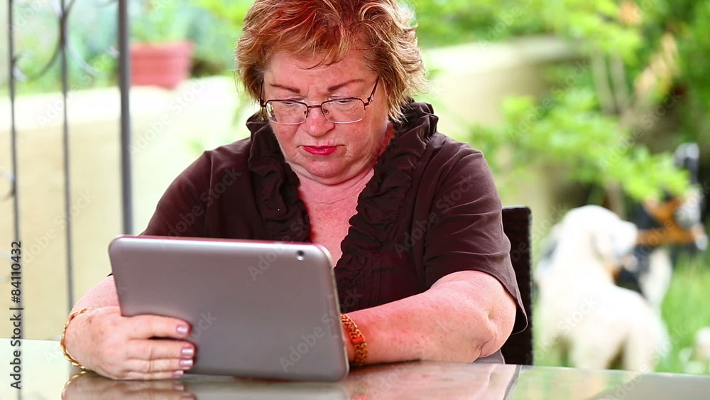 senior woman using digital tablet in a garden senior woman using digital tablet in a garden