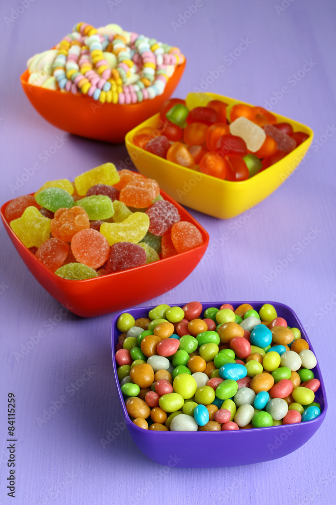 Colorful candies in a bowl on a wooden background
