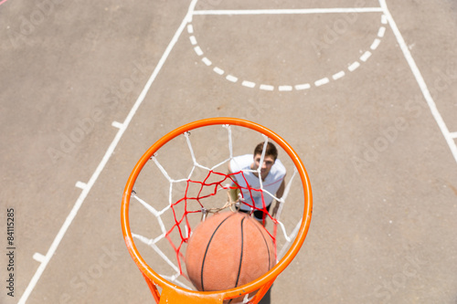 Young Man Playing Basketball with Ball in Net