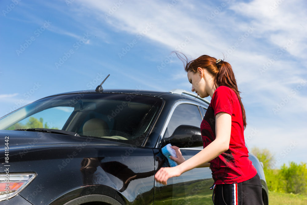Woman Wearing Red Shirt Washing Black Car in Field Woman Wearing Red Shirt Washing Black Car in Field