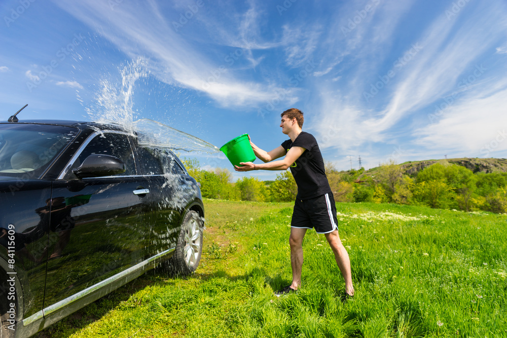 Man Washing Black Car in Green Field
