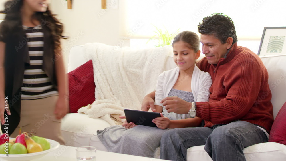 A cute family of four look at something together with their digital tablet A cute family of four look at something together with their digital tablet