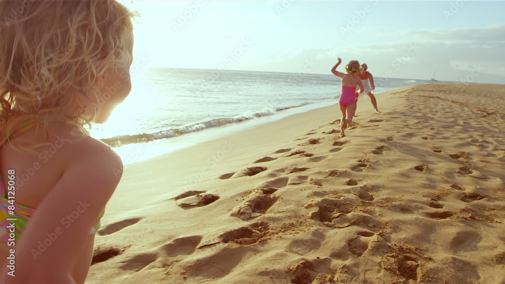 Young girls on a beach run to there mom and give her a big hug as the sun sets 