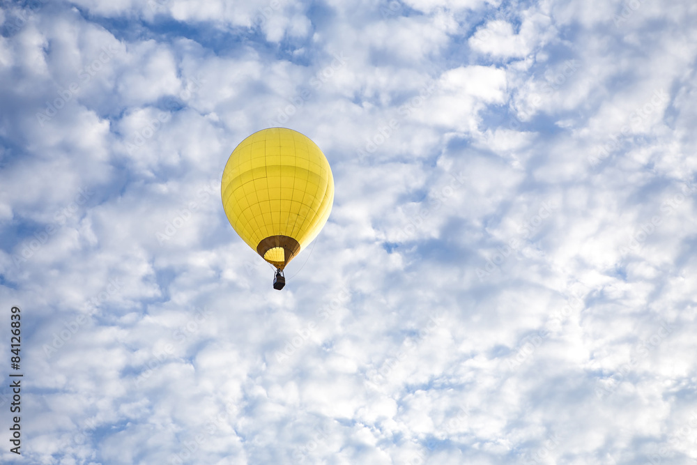 Obraz premium A Yellow Hot Air Balloon floats high in the sky. 