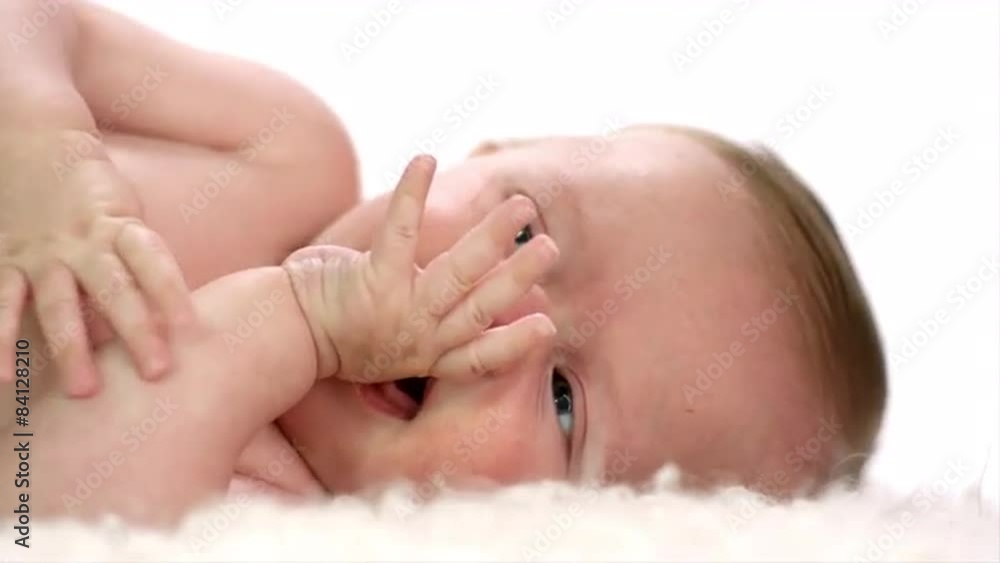 A crying baby lays on a white blanket in a white room A crying baby lays on a white blanket in a white room