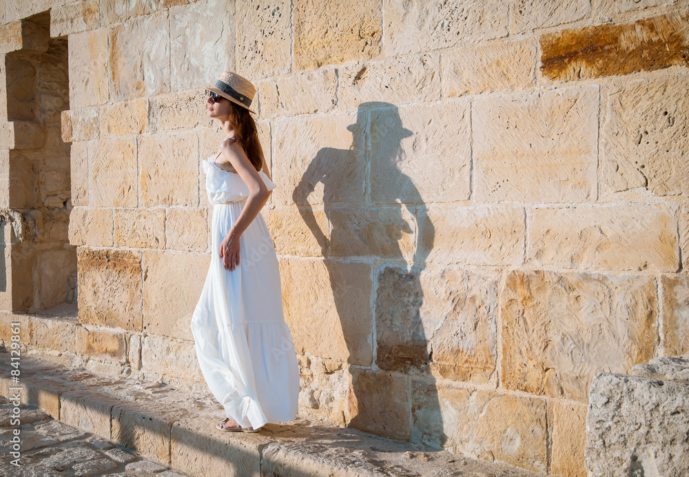 Pretty young woman walking near the stone wall