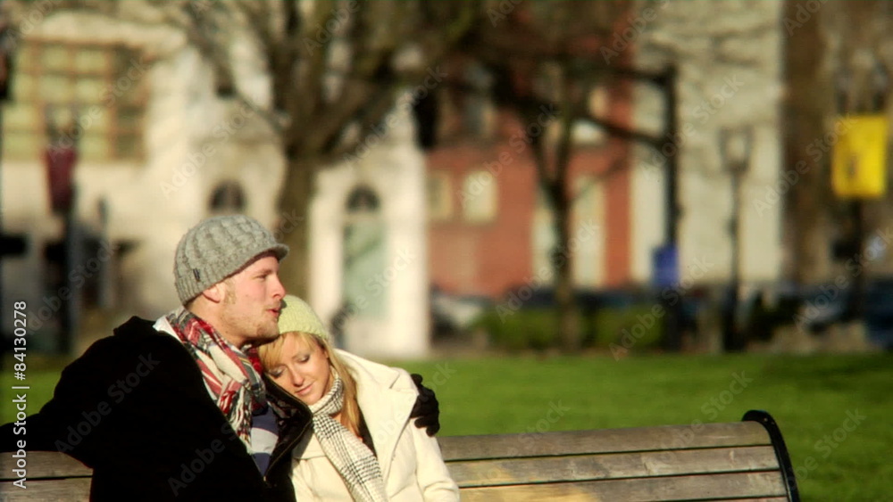 Young man and young woman cuddling on a bench Young man and young woman cuddling on a bench