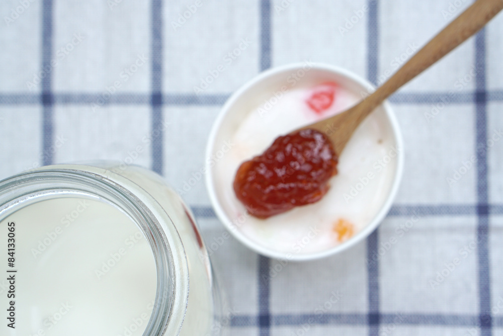 Milk ice cream in white cup with Spoon of strawberry jam backgro Milk ice cream in white cup with Spoon of strawberry jam backgro