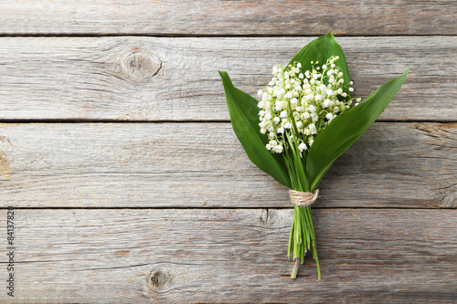 Lily of the Valley with leaves on grey wooden background