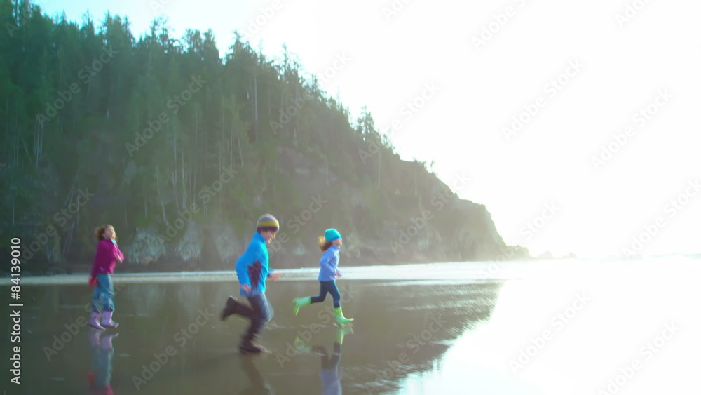 Three kids run down the beach with the camera Three kids run down the beach with the camera
