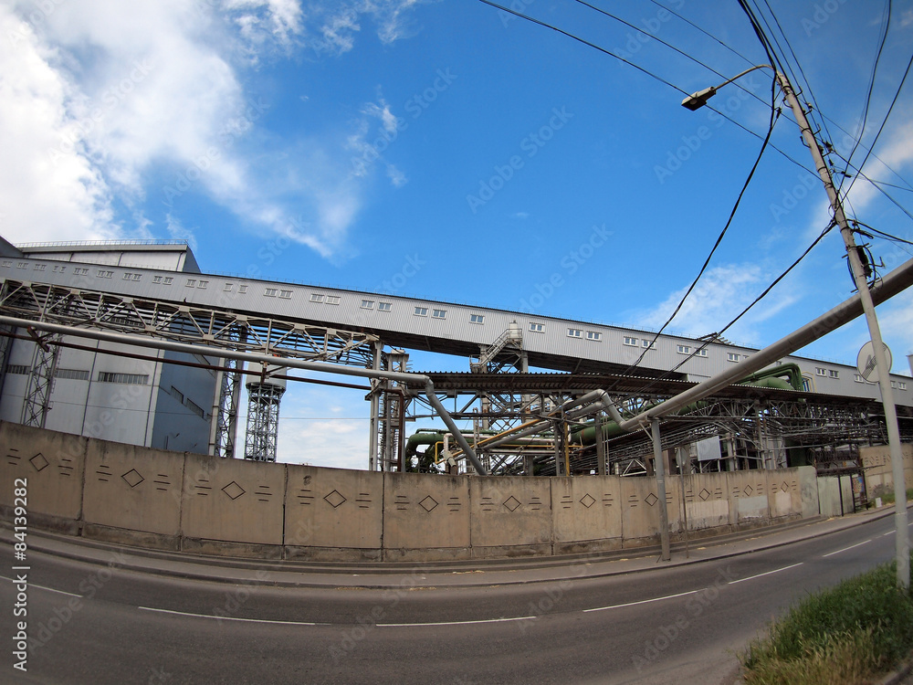 Obraz premium Industrial buildings behind a fence facing the road