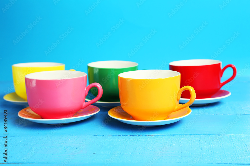 Colorful cups on blue wooden background Colorful cups on blue wooden background
