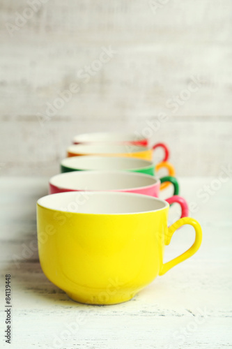 Colorful cups on white wooden background