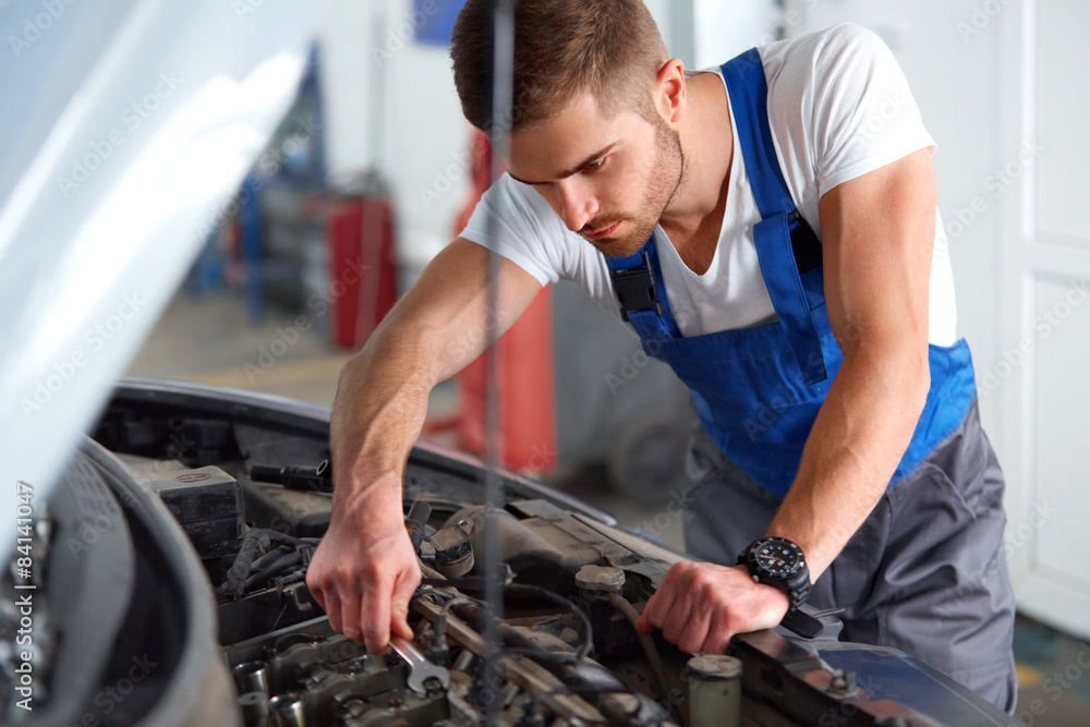 Portrait of a mechanic servicing a car at his workshop Portrait of a mechanic servicing a car at his workshop