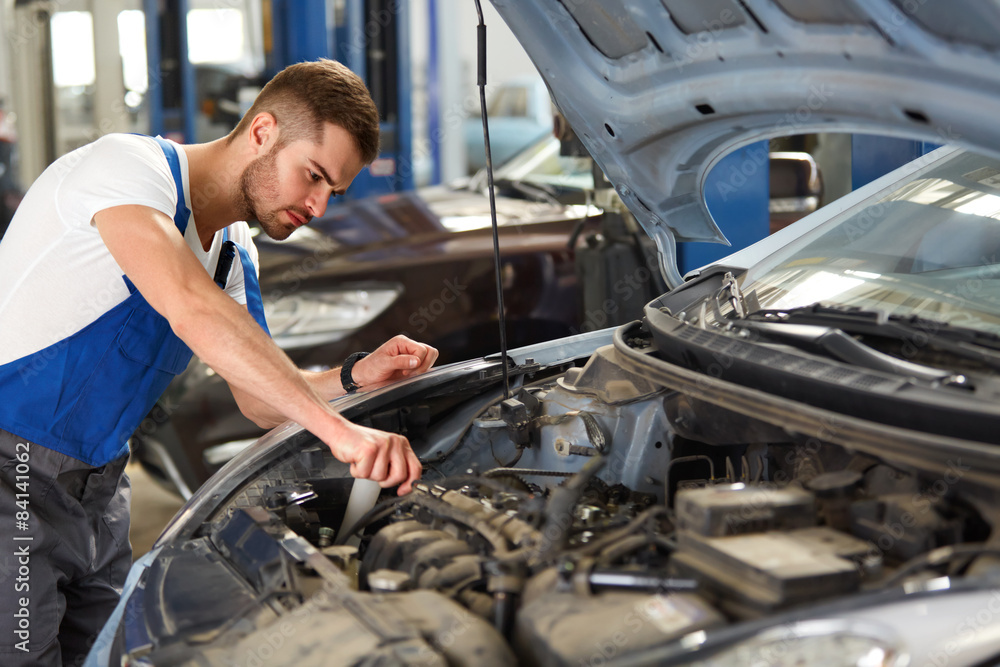 Portrait of a mechanic servicing a car at his workshop Portrait of a mechanic servicing a car at his workshop
