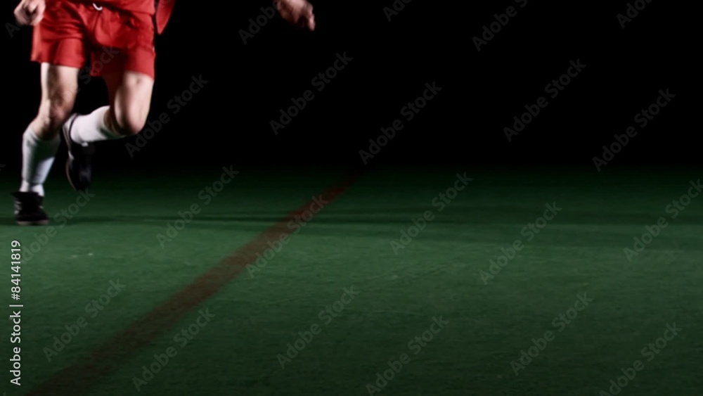 Wide shot of a soccer player approaching the ball and kicking it with power Wide shot of a soccer player approaching the ball and kicking it with power