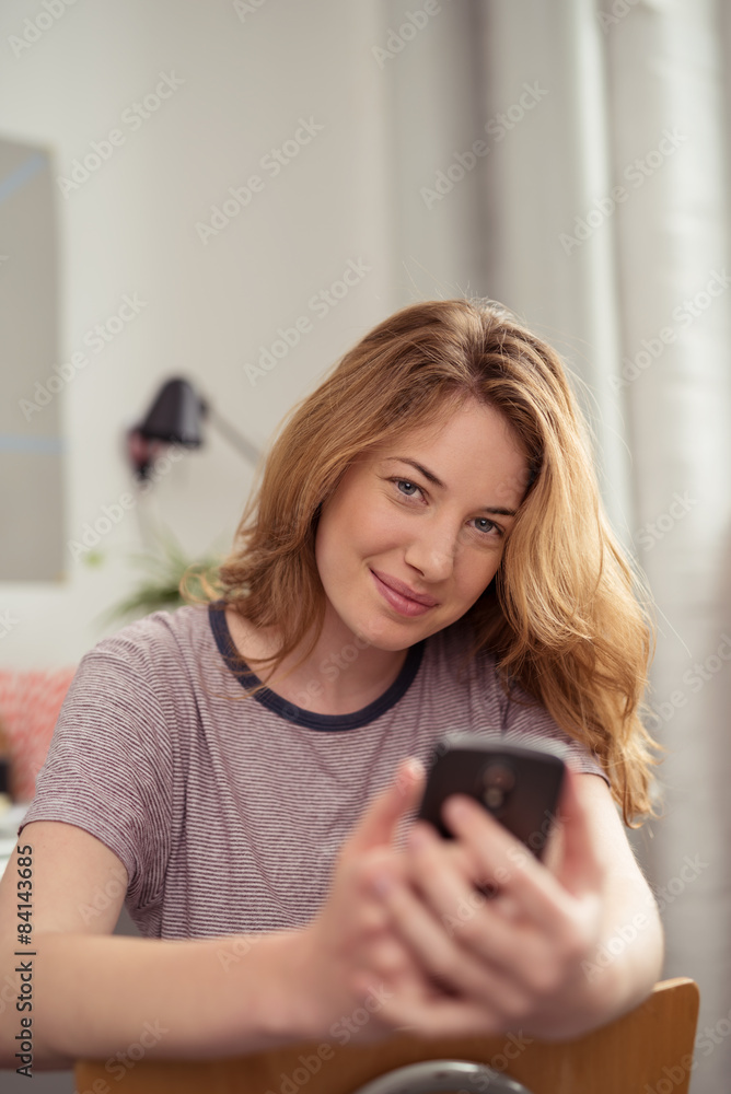 studentin sitzt zuhause und hält ihr handy in der hand studentin sitzt zuhause und hält ihr handy in der hand