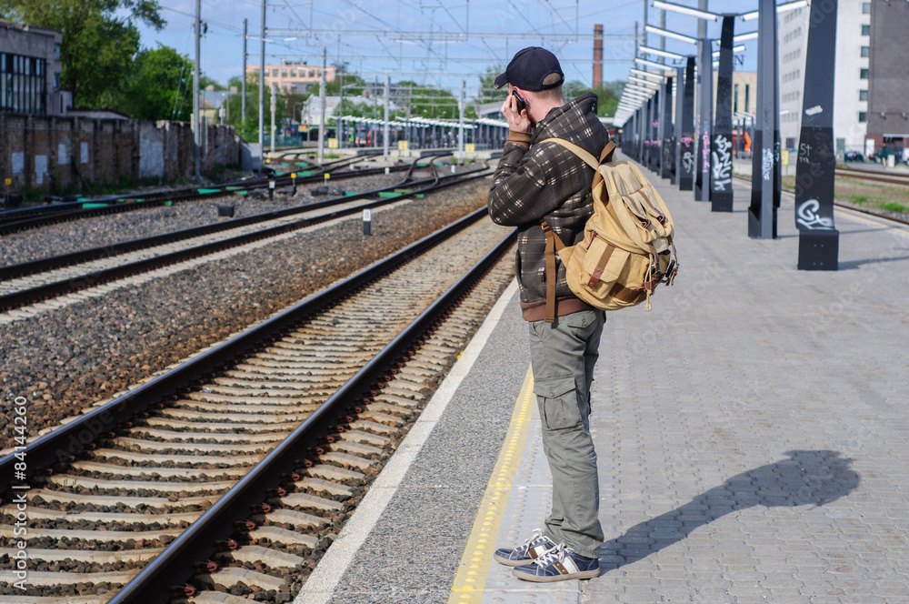 Young man waits train on railway station Young man waits train on railway station