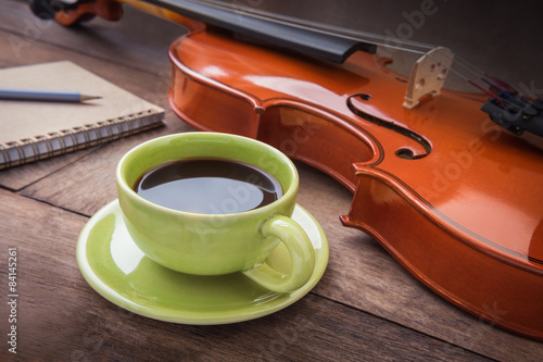 Coffee cup with violin and book on wooden table