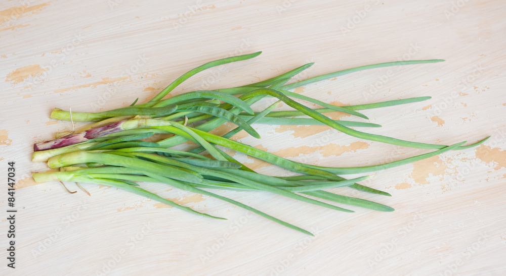 First spring green onions on a tacky white-colored wooden table First spring green onions on a tacky white-colored wooden table