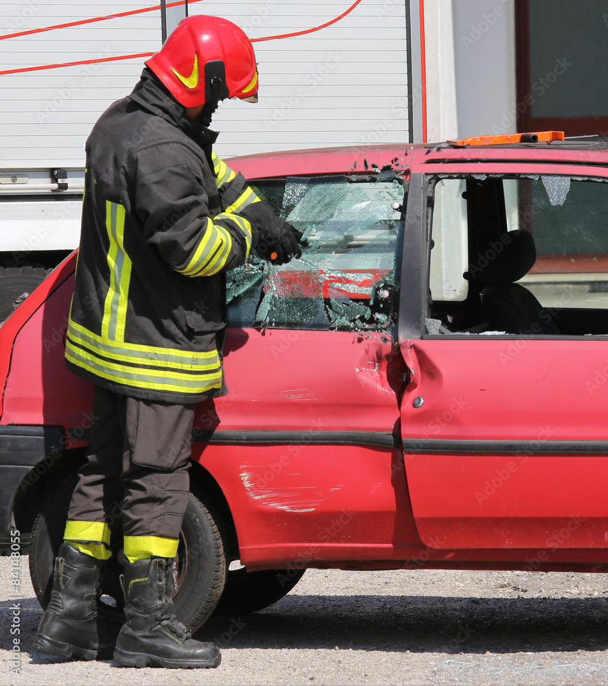 chief fireman while breaking the glass of a car with a special e chief fireman while breaking the glass of a car with a special e