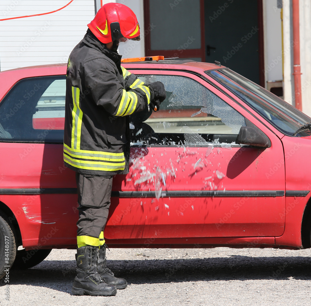 fireman while breaking the glass of a car with a special equipme fireman while breaking the glass of a car with a special equipme