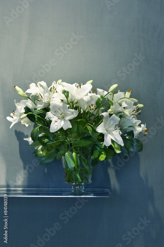 Fototapeta Naklejka Na Ścianę i Meble -  White lilies in a flower vase with blue background