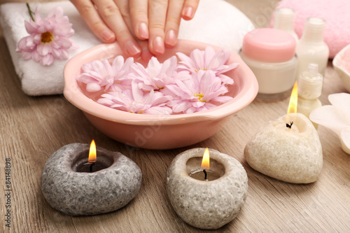 Female hands and bowl of spa water with flowers  closeup