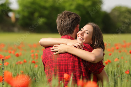 Couple hugging after proposal in a flower field