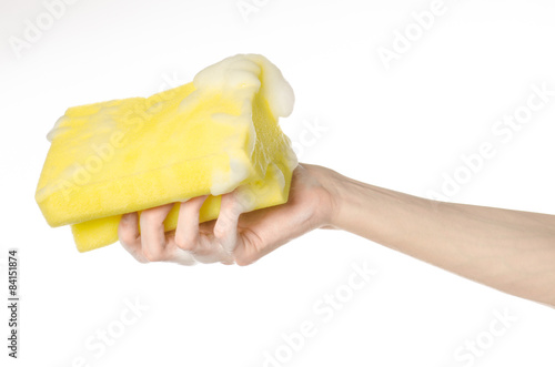 Hand holding a yellow sponge wet with foam isolated studio
