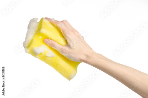 Hand holding a yellow sponge wet with foam isolated studio