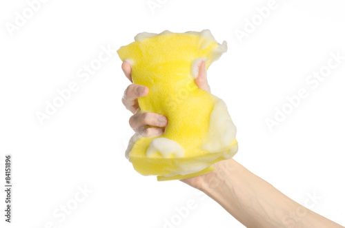 Hand holding a yellow sponge wet with foam isolated studio