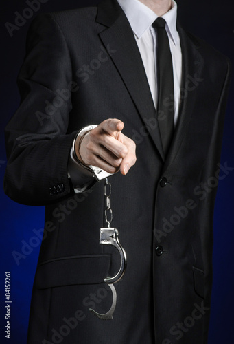 businessman in a black suit with handcuffs on his hands studio