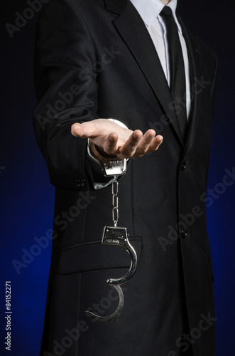 businessman in a black suit with handcuffs on his hands studio