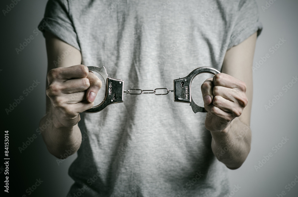 Fototapeta premium man with handcuffs on his hands in a gray T-shirt in the studio