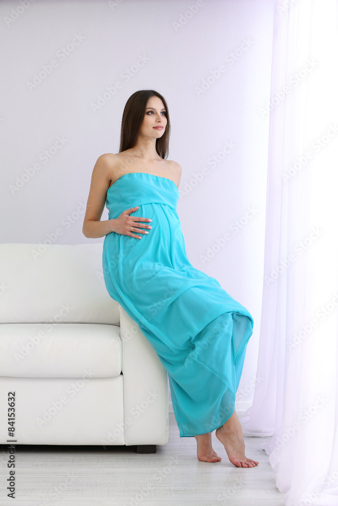 Pregnant woman sitting on sofa in room