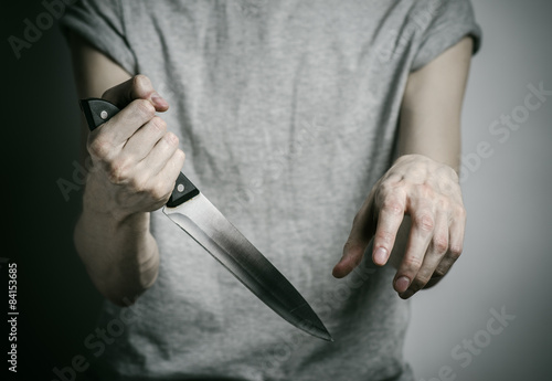 a man holding a knife on a gray background studio