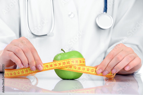 Nutritionist doctor with apple and measuring tape, closeup