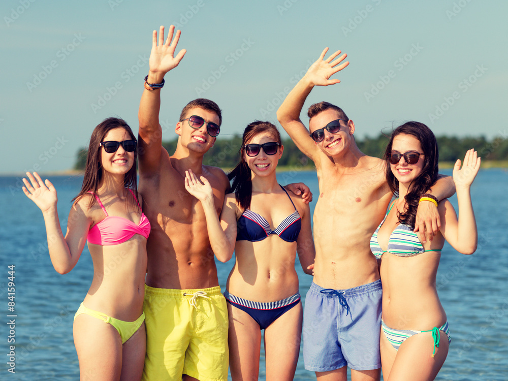 smiling friends in sunglasses on summer beach