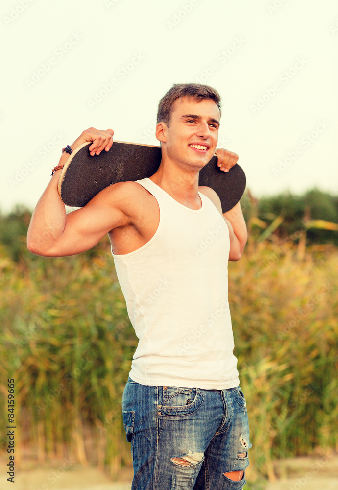 Fototapeta premium smiling teenage boy with skateboard outdoors