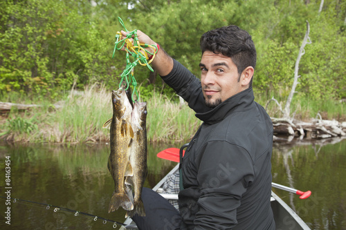 Young Hispanic fisherman holds up a stringer of walleyes
