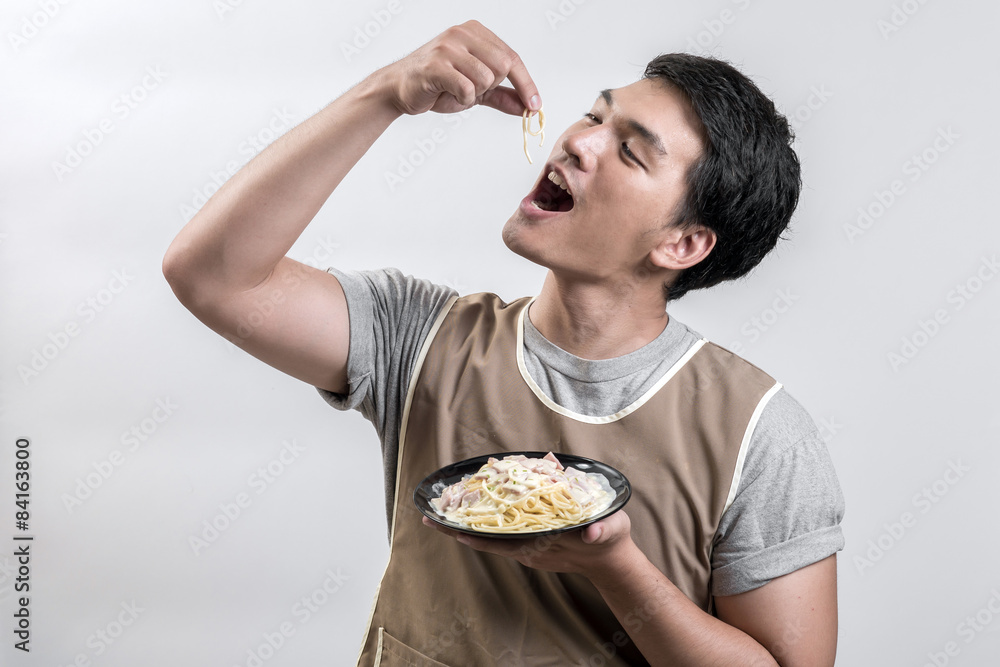Asian man in apron with spaghetti carbonara Asian man in apron with spaghetti carbonara