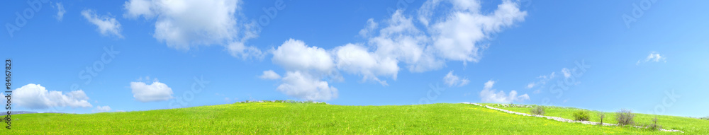 Collina verde all'aperto con nuvole nel cielo blu chiaro - obrazy, fototapety, plakaty 