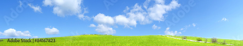 Collina verde all'aperto con nuvole nel cielo blu chiaro