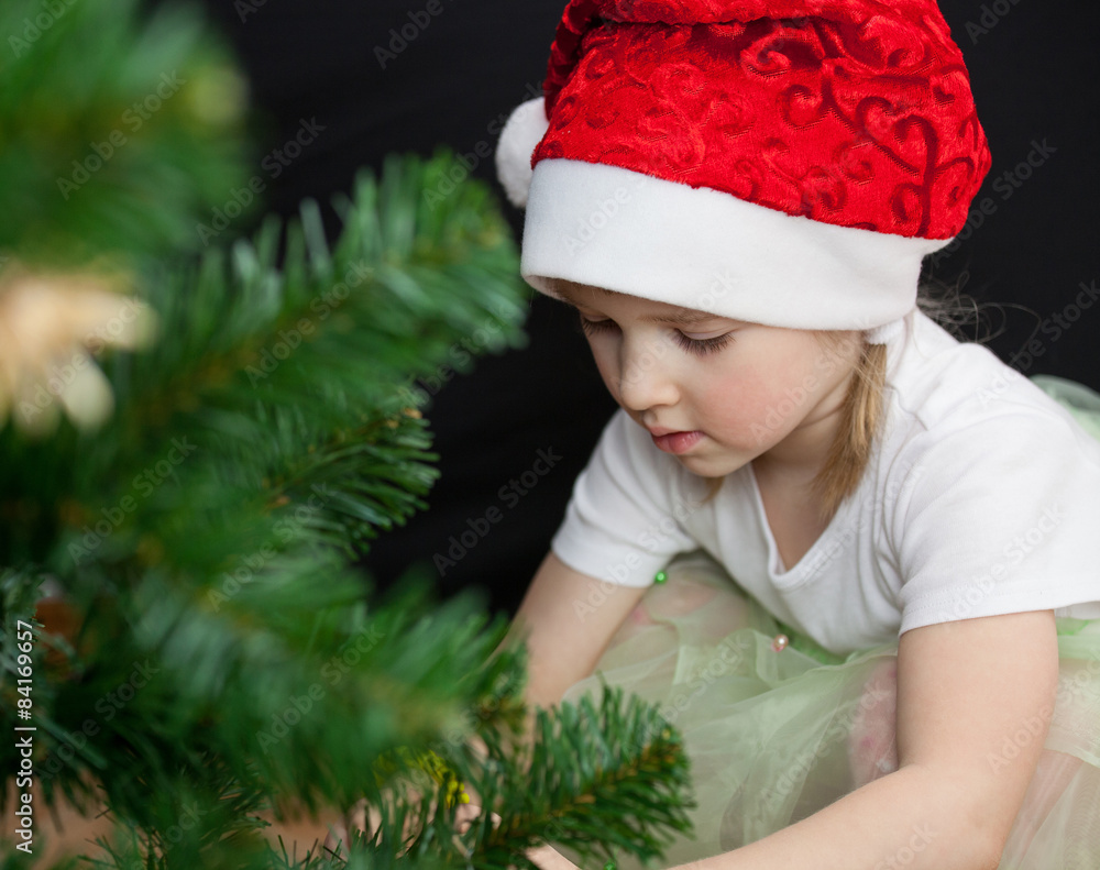 Beautiful little girl decorates the Christmas tree