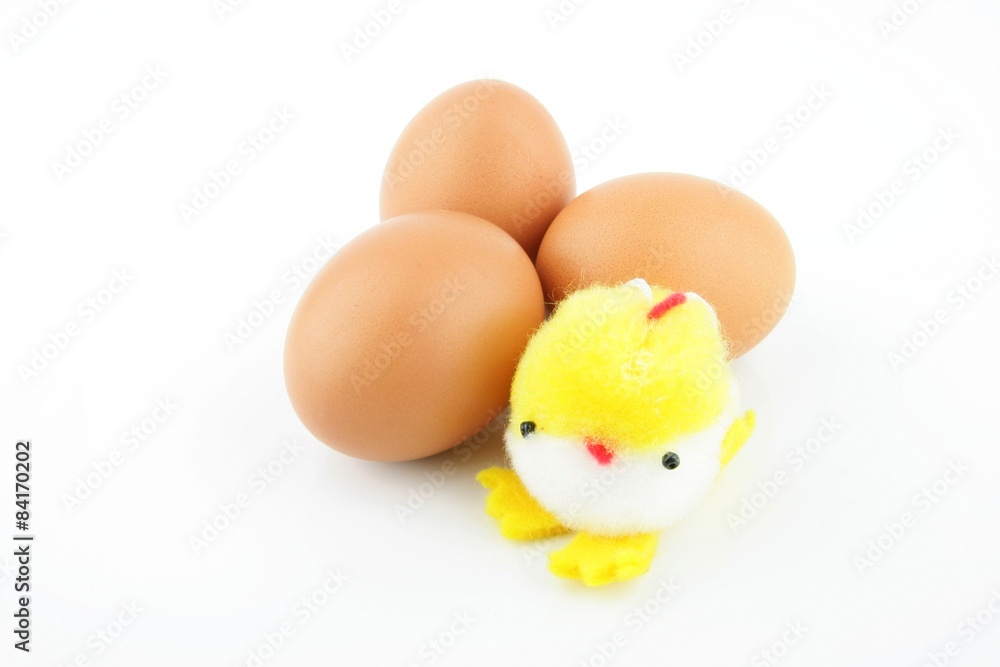 Little yellow stuffed easter chick on top of three eggs, on a white background.