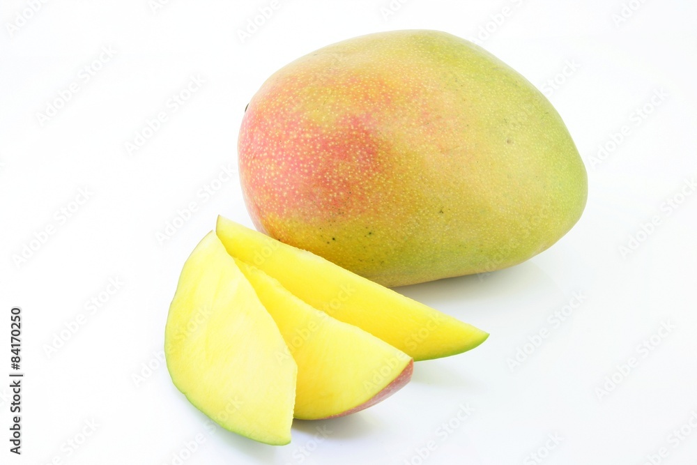 Fresh ripe mango (Mangifera indica) with some slices on a white background.