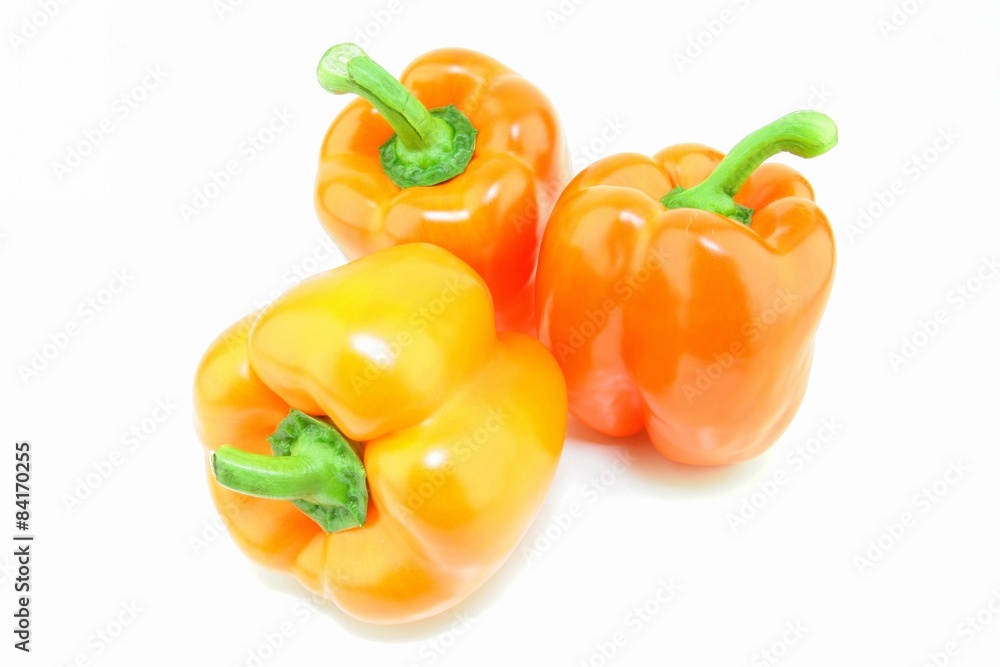 A group of fresh orange paprika (Capsicum annuum) on a white background. A group of fresh orange paprika (Capsicum annuum) on a white background.