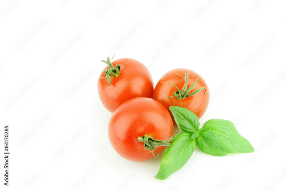 three fresh ripe tomatoes with some basil leaves on a white background. three fresh ripe tomatoes with some basil leaves on a white background.