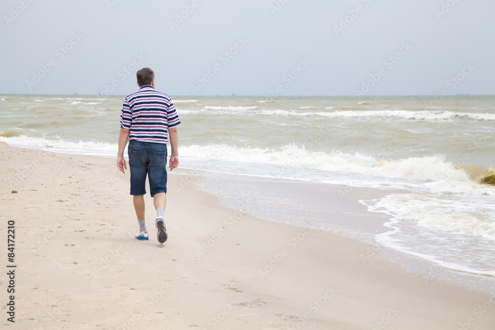 Man walks on the sea beach